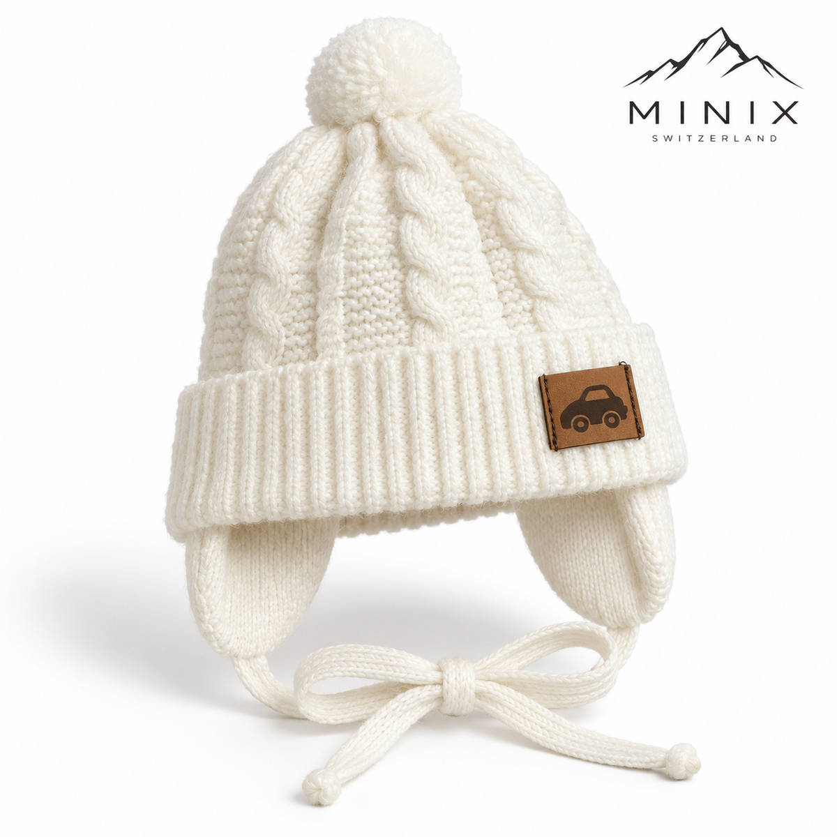 Cream cable-knit baby cap with pompom, car patch and ear flaps – angled view