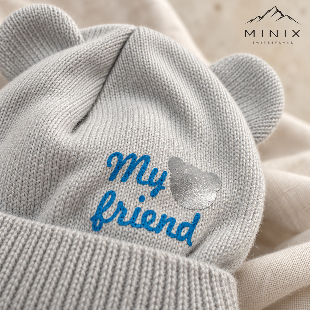 Close-up of the blue "My friend" lettering and silver bear patch on the grey knitted cap