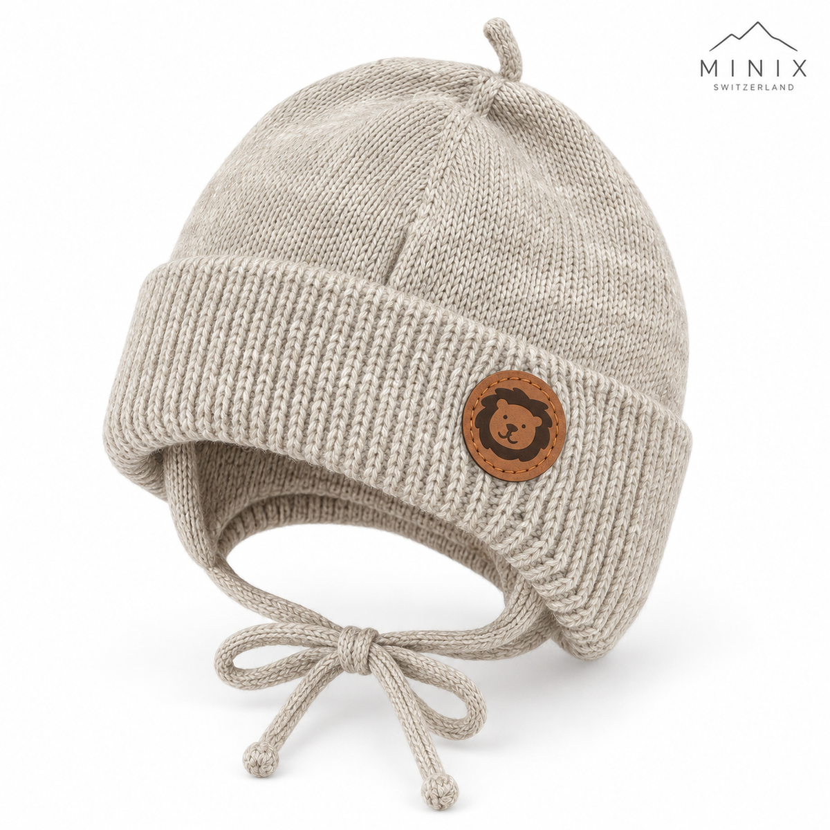 Beige knitted baby cap with lion patch and loop on top – angled view