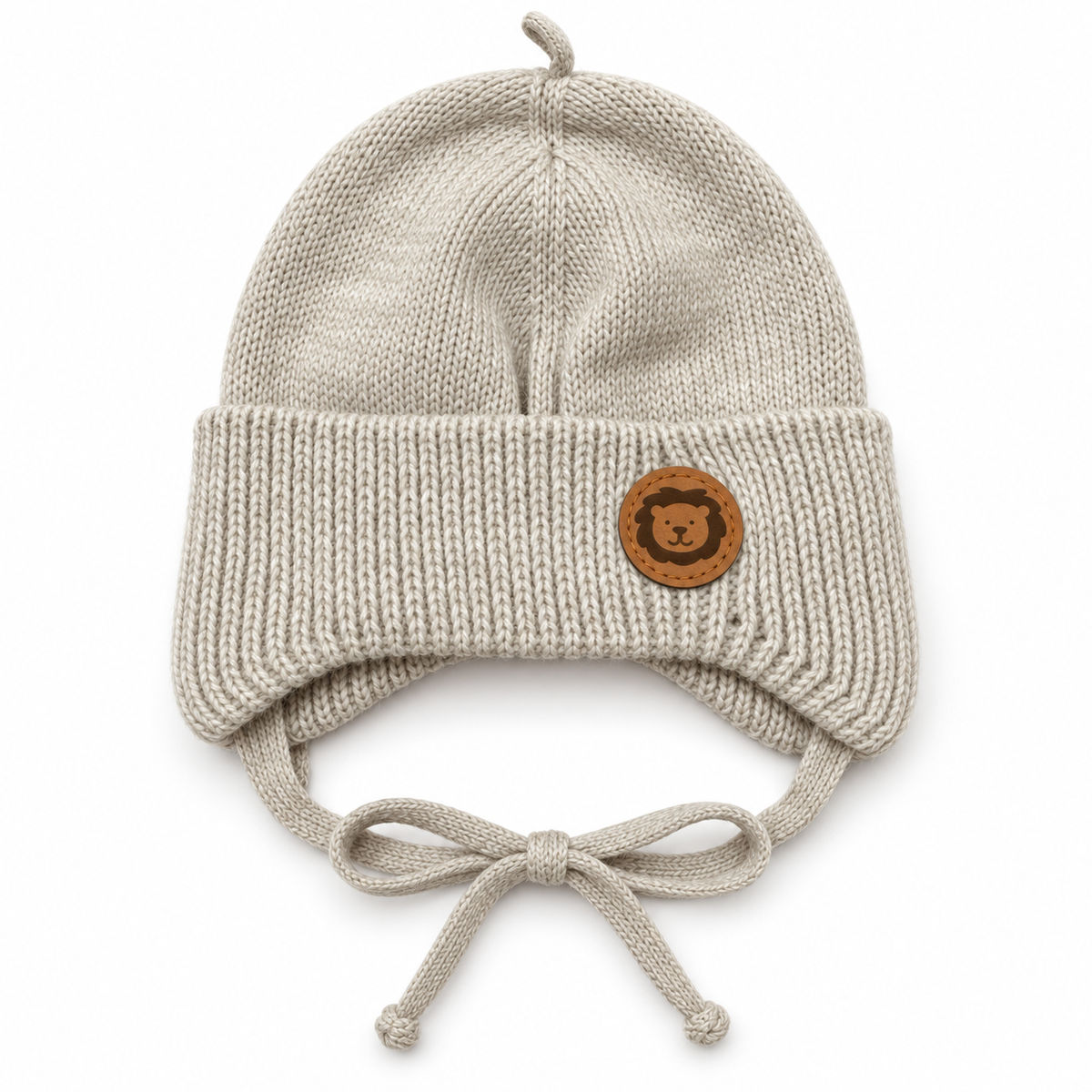 Beige knitted baby cap with lion patch, ear flaps and bow ties – flat front view