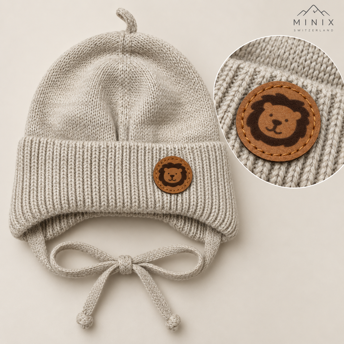 Beige knitted baby cap with lion patch – flat lay with close-up of the lion leather-look patch