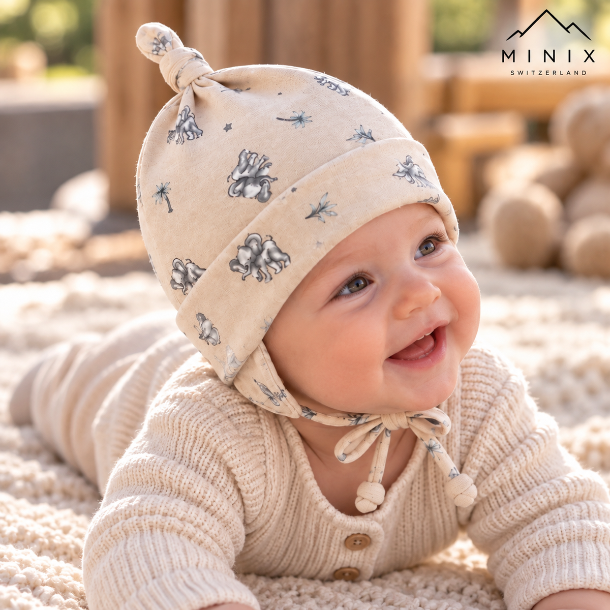 Baby wearing the beige MINIX cotton knot cap with elephant and star print