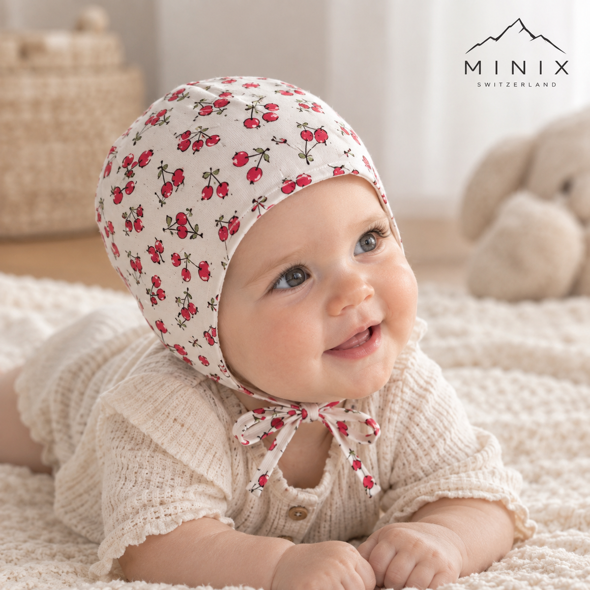 Baby wearing the white MINIX cotton bonnet with cherry print and tie strings