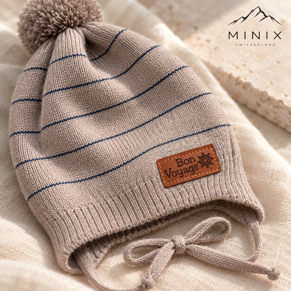 Close-up of the Bon Voyage ship's wheel patch and navy stripes on the beige knitted cap