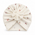 Girls cream cotton turban cap with ditsy floral print and pleated bow – flat lay product shot by MINIX Switzerland