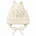 Cream cable-knit baby girl cap with rhinestones, knitted bow, ear flaps and tie strings – front view