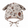 Baby boy wearing beige dog ear cotton cap with Woof print outdoors by a Swiss lake – lifestyle shot by MINIX Switzerland