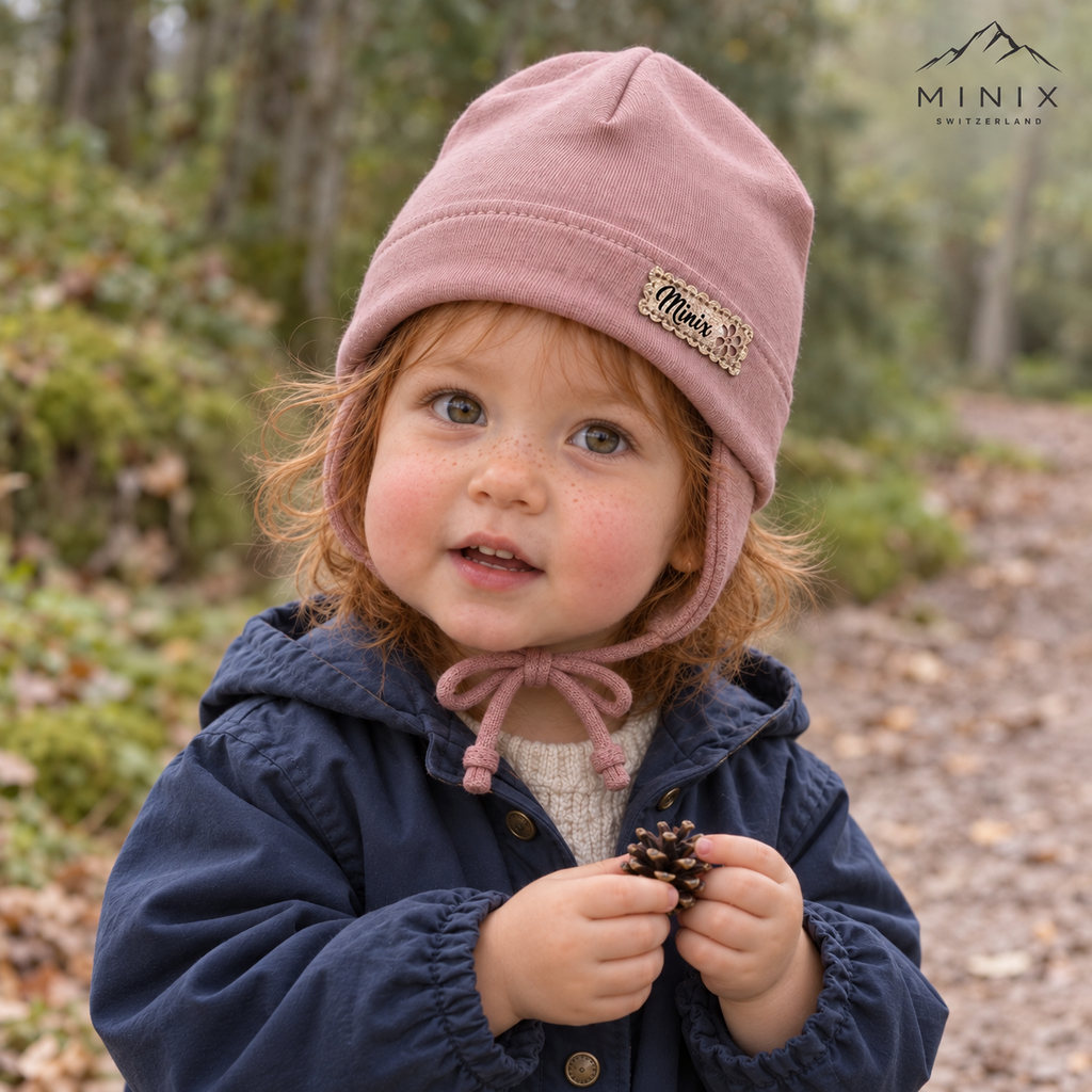 Child wearing the dusty rose MINIX cotton cap with ear flaps and tie strings