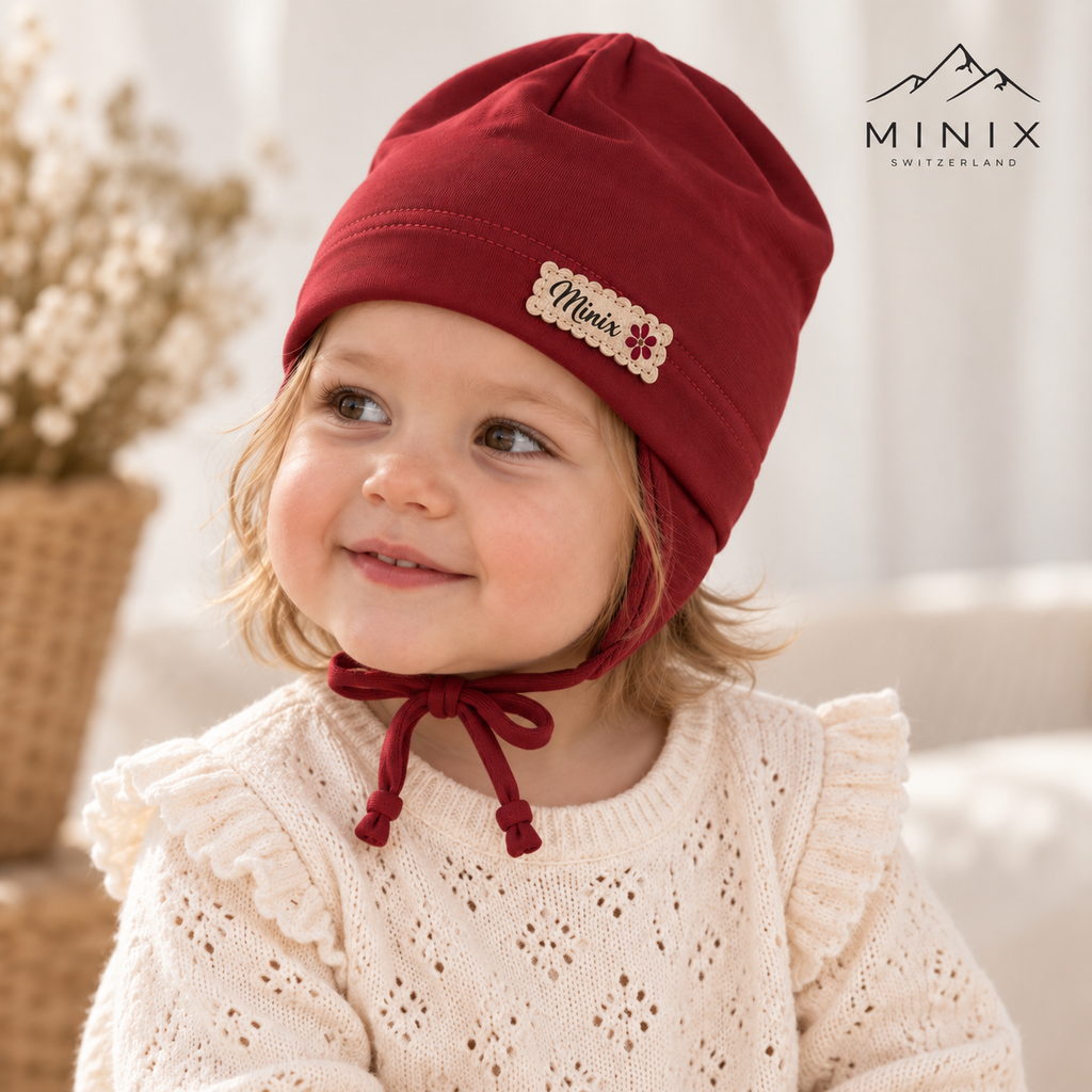 Child wearing the burgundy MINIX cotton cap with ear flaps and tie strings