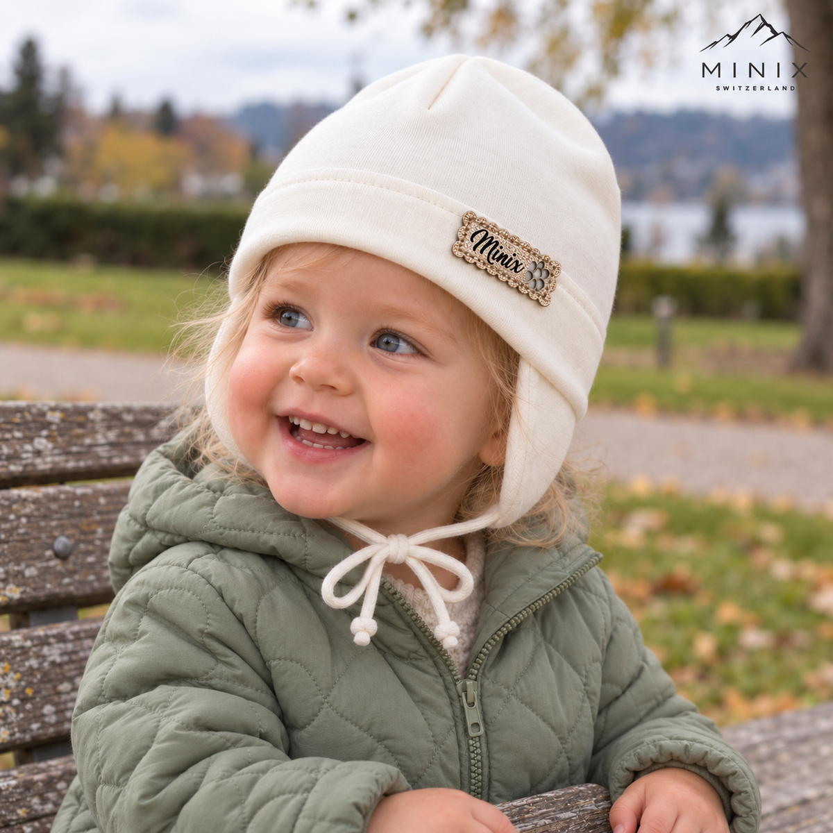 Child wearing the cream MINIX cotton cap with ear flaps and tie strings