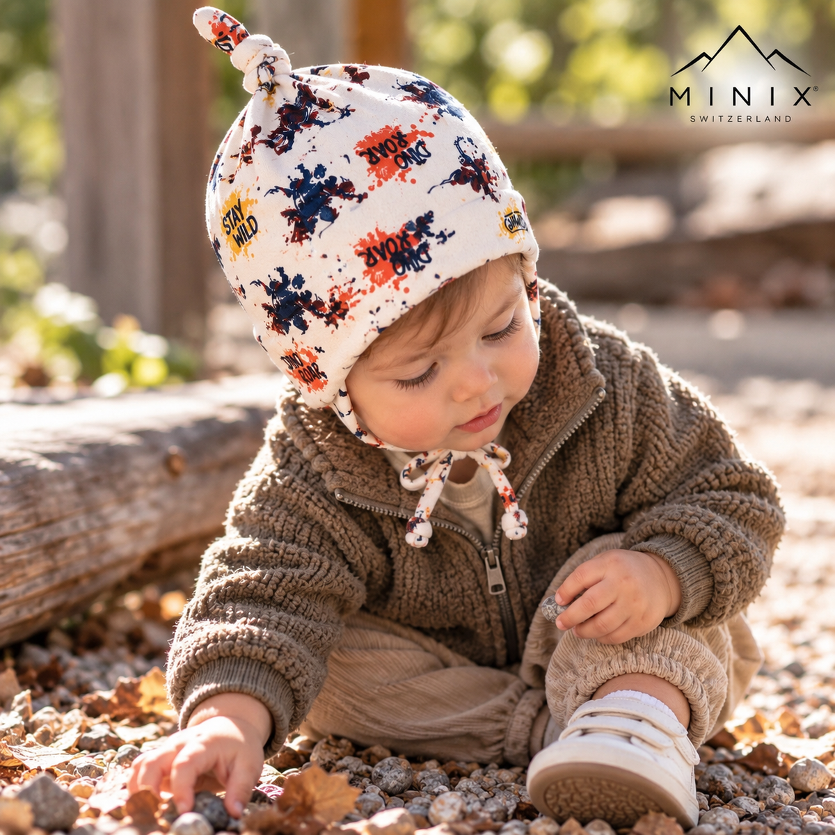 Toddler wearing the white MINIX cotton knot cap with Dino Roar dinosaur print