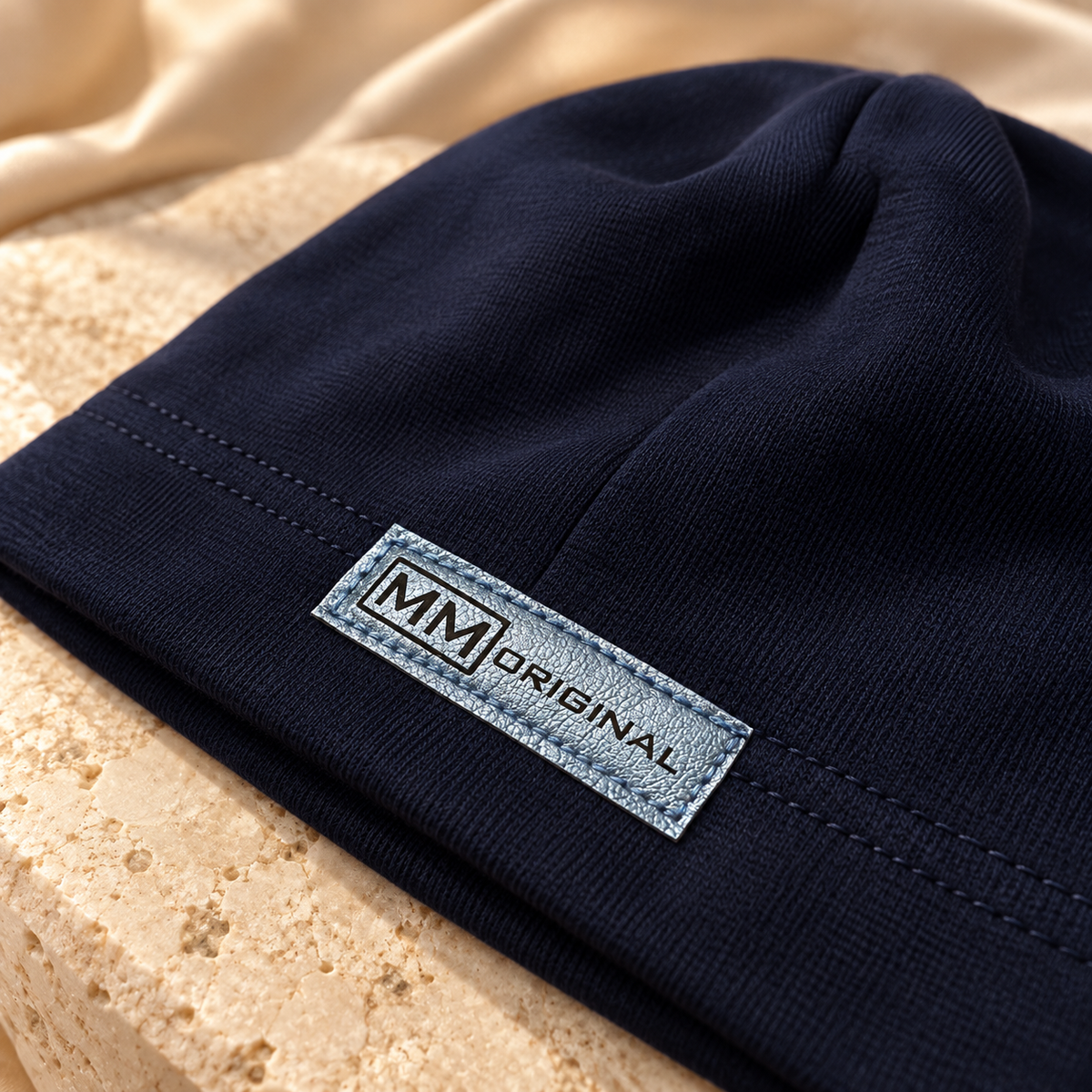 Close-up of the metallic MM Original label on a navy kids cotton beanie