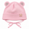 Pink knitted baby girl cap with sparkly round ears, little m patch on the cuff and tie strings – front view