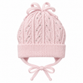 Light pink cable-knit baby girl cap with rhinestones, knitted bow, ear flaps and tie strings – front view
